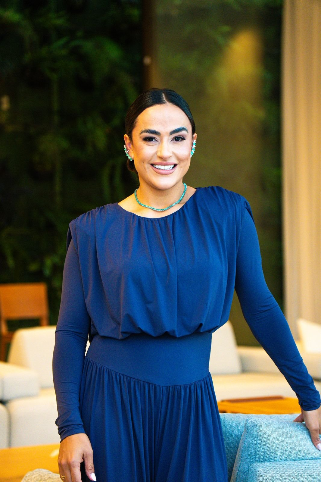 Camila Meneses sorrindo, de vestido azul-marinho