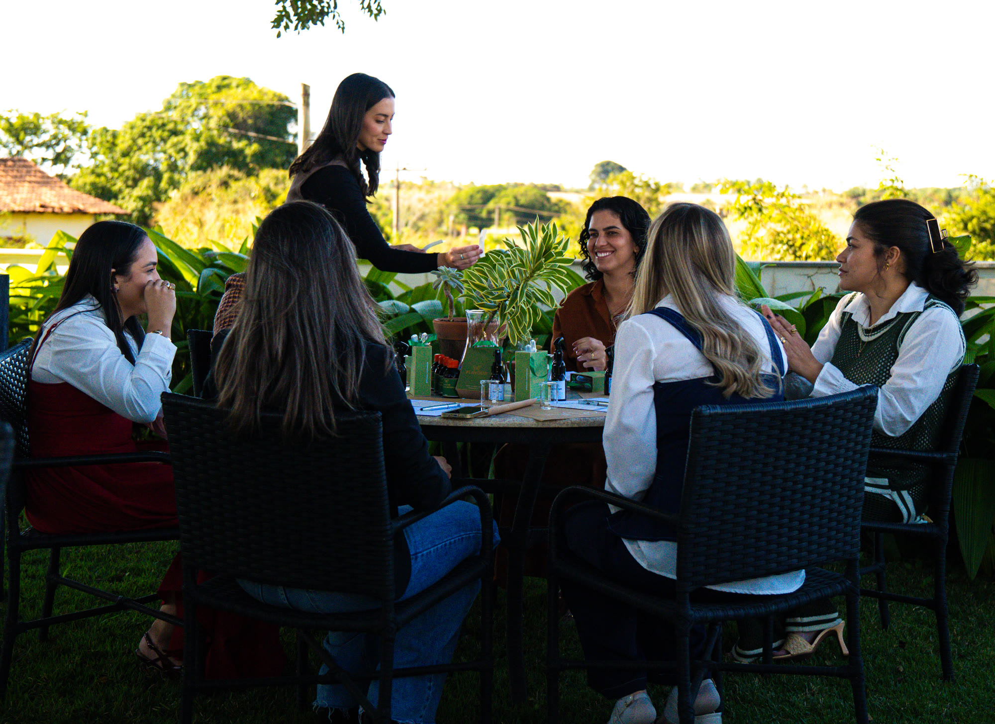 Mulheres reunidas à mesa em um jardim durante o Essência do Lar